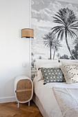 Bed against panel with palm-tree motif in classic bedroom