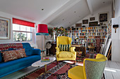 Upholstered seating in yellow and blue in small living room with colourful accessories