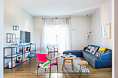 Metal shelves, fifties chairs and blue sofa in light-flooded living room