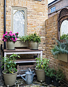 Plants on console table in courtyard garden with brick walls