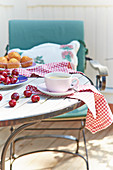 Tasse Kaffee, Kirschen und Muffins auf sommerlichem Gartentisch