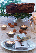 Chocolate torte and tealights in tiny flan tins on festively set table
