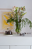 Wintry flower arrangement of amaryllis and pine cones under glass cover