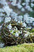 Wreath of moss and twigs decorated with bird figurines and flowering branches