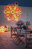 Weißer Shabby-Holztisch auf abendlicher weihnachtlich dekorierter Terrasse