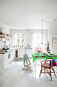 White kitchen-dining room with white floor and brightly coloured accents