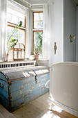 Alte blaue Truhe vorm Erkerfenster im sonnigen Schlafzimmer