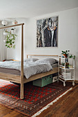 Modern wooden bed with high foot on Persian rug