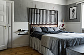 Double bed with headboard made from reclaimed wood and metal in bedroom with grey walls