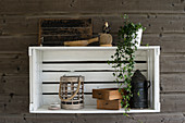 White wooden crate used as shelving unit and vintage-style accessories on grey board wall