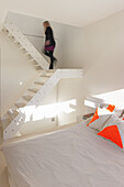 Modern white staircase construction above double bed