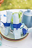 Handmade napkin rings with blue bird motifs on table set for summer meal in garden