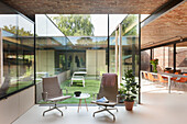Offener Wohnbereich mit Sitzmöbeln und Glaswänden mit Blick zum Innenhof
