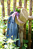 Denim jacket and summer hat decorated with flowers hung on fence