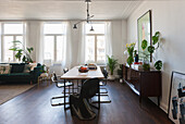 Offener Wohnbereich mit Holztisch, schwarzen Stühlen und Zimmerpflanzen
