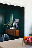 Vintage side table with mirror in a room with dark green walls