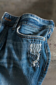 Seam detail of repaired blue jeans on concrete background