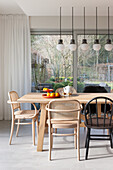 Dining area with wooden table, various chairs and pendant lights