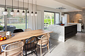 Open-plan kitchen with island, dining table, pendant lights and view of the yard