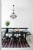 Black metal chairs around table on striped rug in dining room