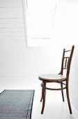 Alter Stuhl auf weißem Boden unterm Dachfenster