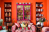 Sofa with ethnic pattern in front of orange wall with shelves in niches