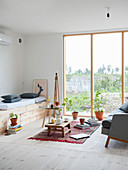 Eingebaute Sitzbank aus hellem Holz, Coffeetable und Couch vor raumhohem Fenster