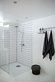 Ebenerdige Dusche im Bad ganz in Weiß mit schwarzen Accessoires