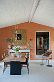 Rustic dining table in front of terracotta-coloured wall
