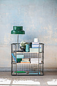 Ornaments in shades of blue and green on metal shelves against distressed wall