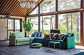 Sofa aus verschiedenen Elementen in Grün und Blau vor Fensterfront