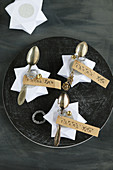 Place cards made from DIY origami stars and antique spoons with stamped mottoes on labels