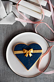 Large heart-shaped biscuit with blue fondant icing and golden bow