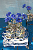 Cornflowers in small bottles with decoration