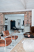 Leather armchairs in living room with brick wall and white floor