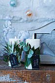 Candles decorated with eucalyptus branches, olive and bay leaves and mottoes