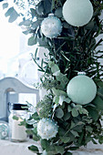 Garland of eucalyptus, olive and bay branches decorated with Christmas baubles