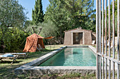 Tent used as sun shade next to swimming pool in Mediterranean garden