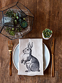 Easter place setting with linen napkin and arrangement of succulents on wooden table