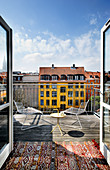 Metal furniture on sunny roof terrace overlooking colourful neighbouring buildings
