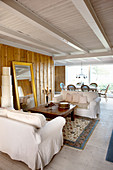 Wohnzimmer im Landhausstil mit weißen Hussen-Sofas und Goldrahmen-Bodenspiegel