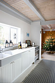 White country-house kitchen with open doorway leading into festively decorated Christmas tree
