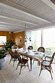 Gedeckter Esstisch mit Bambusstühlen in weihnachtlich dekoriertem Wohnraum