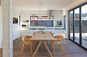 Open-plan cooking and dining area with modern kitchen and wooden dining table and chairs