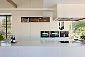 Moderne Küchenzeile mit weißer Arbeitsplatte, Schränken und Einbaugeräten