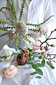 Making a spring bouquet of banksia, tulips, ranunculus, carnations, freesias, branches of magnolia and eucalyptus