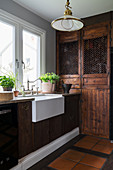 Belfast sink in rustic country-house kitchen with dark wooden cabinets