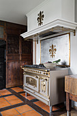 Antique, solid fuel cooker decorated with fleur-de-lis in rustic kitchen
