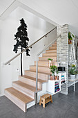 Wall decal with tree motif next to modern wooden stairs in hallway