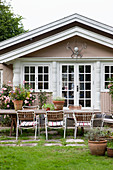 Tisch und Stühle auf der Terrasse vorm rustikalen Landhaus